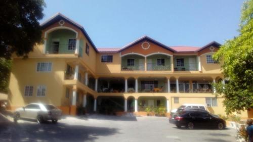 a large yellow building with cars parked in a parking lot at Palm Bay Guest House & Restaurant in Montego Bay