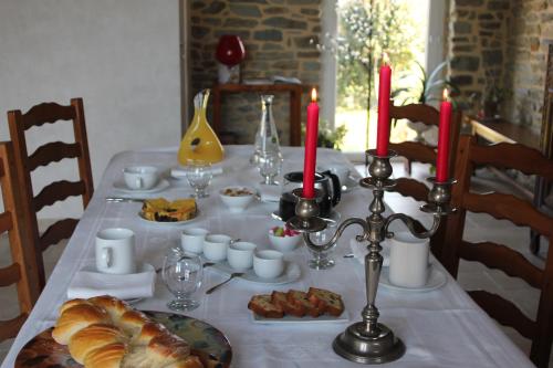 Au p'tit Mont في Ardevon: طاولة مع قطعة قماش بيضاء مع الطعام والشموع