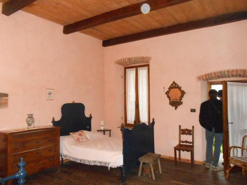 un homme debout dans une chambre avec un lit et une fenêtre dans l'établissement B&B Cascina Marie, à Bricherasio