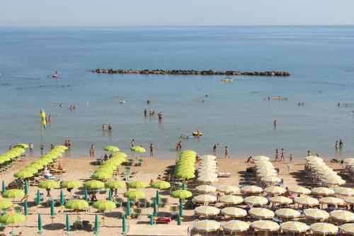 a beach with many umbrellas and people in the water at Hotel Caesar in Pesaro