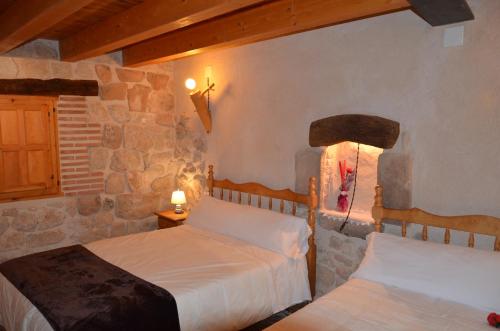 a bedroom with two beds and a stone wall at Casa LLovet in Fuentespalda