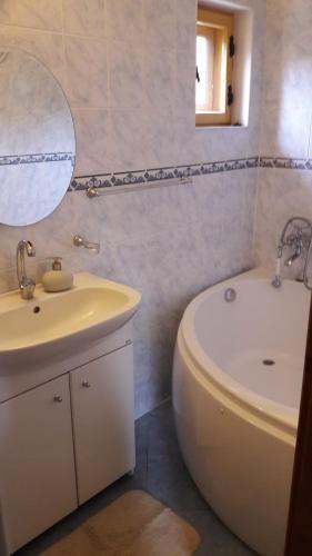 a bathroom with a sink and a tub and a mirror at Chalupa JANINA in Terchová