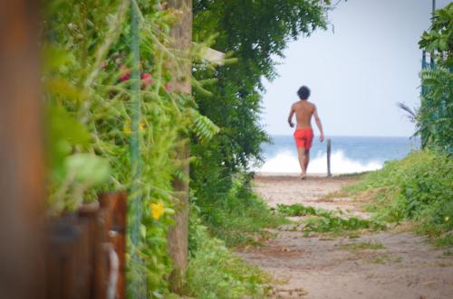 a man walking down a path towards the ocean at Vibra Guesthouse Popoyo in Popoyo