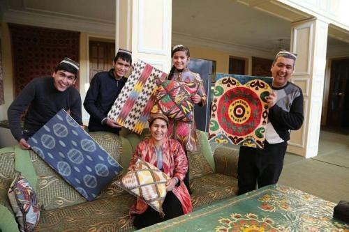 a group of people holding up a pile of pillows at Guest House Ikathouse in Margilan