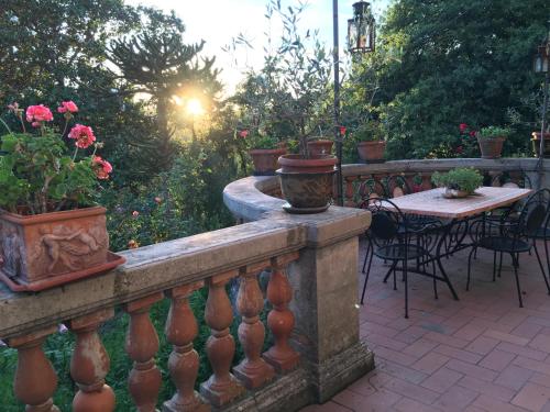 a stone fence with a table and chairs and flowers at Villa Baronzola in Montevarchi