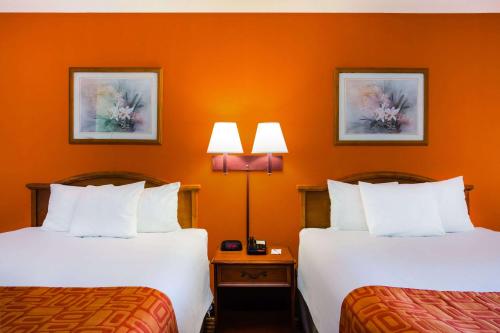 two beds in a hotel room with orange walls at Howard Johnson by Wyndham Panama City in Panama City