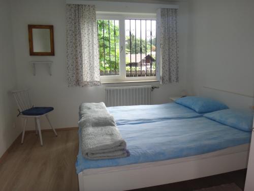 Schlafzimmer mit einem Bett mit blauer Bettwäsche und einem Fenster in der Unterkunft Ferienbungalow in Seeboden