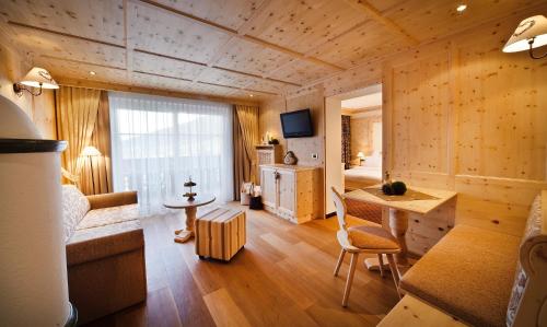 a living room with a bed and a desk in a room at Alpin Garden Luxury Maison & SPA - Adults Only in Ortisei