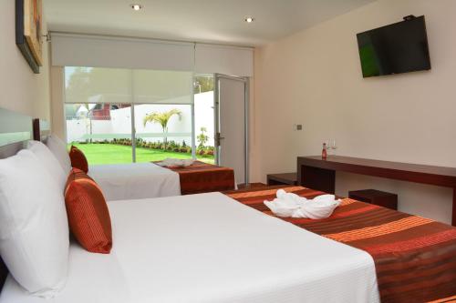 a hotel room with two beds and a television at Hotel Quinta Tequisquiapan in Tequisquiapan