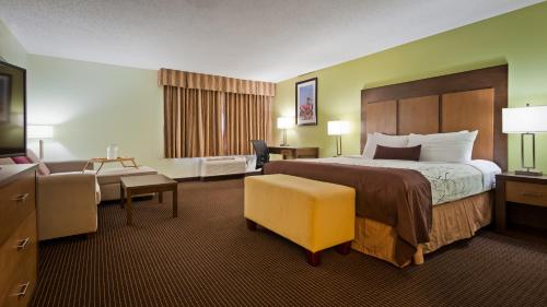 a hotel room with a large bed and a chair at White Pine Inn & Suites in Holland