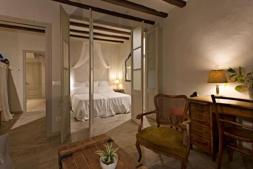 a bedroom with a bed and a chair and a desk at El Jardinet de Sant Esteve in Olot