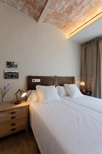 a bedroom with a large white bed and a night stand at El Jardinet de Sant Esteve in Olot