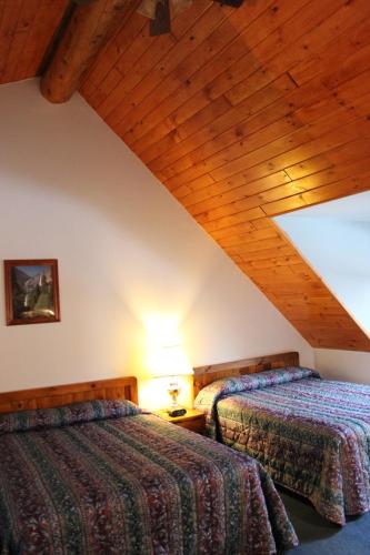 two beds in a room with a wooden ceiling at Nootka Lodge in Woodsville