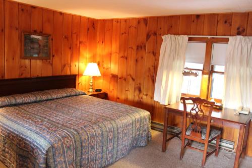 a bedroom with a bed and a desk and a window at Nootka Lodge in Woodsville