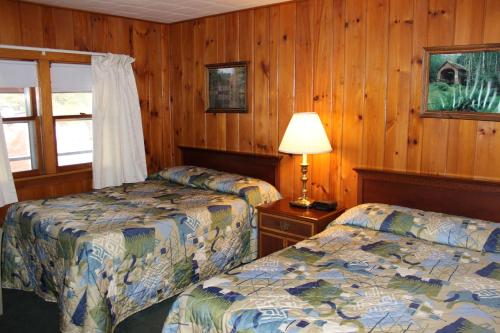 two beds in a room with wood paneled walls at Nootka Lodge in Woodsville