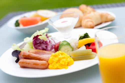 a plate of food with vegetables and a glass of orange juice at Hotel Izukyu in Shimoda