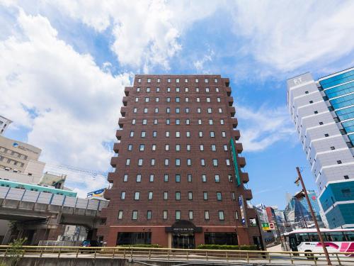un grand bâtiment brun au milieu d'une ville dans l'établissement Nishitetsu Inn Tenjin, à Fukuoka
