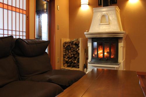 a living room with a fireplace and a couch at Hanaichi in Tsumagoi