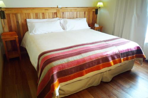 a bedroom with a bed with a striped blanket on it at Hosteria Senderos in El Chalten