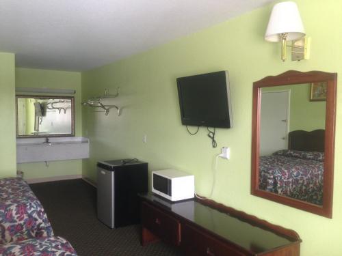 a hotel room with a bedroom with a bed and a mirror at Budget Inn in Donalsonville
