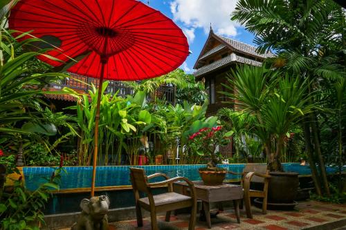 a table with a red umbrella next to a pool at Hongkhao Village in Chiang Mai