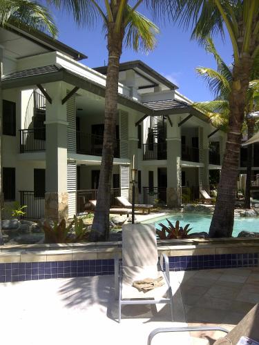 a chair in front of a building with a swimming pool at Penthouse 239 at See Temple Port Douglas in Port Douglas