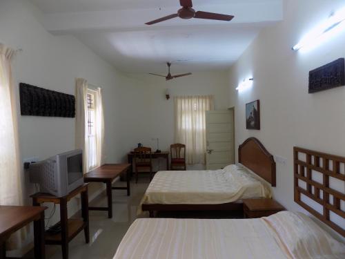 a bedroom with two beds and a tv in it at Safire Residency in Trivandrum