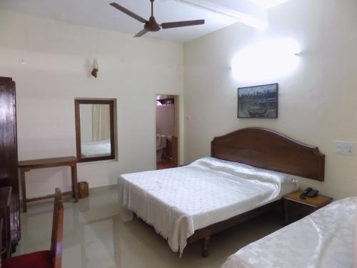 a bedroom with two beds and a ceiling fan at Safire Residency in Trivandrum