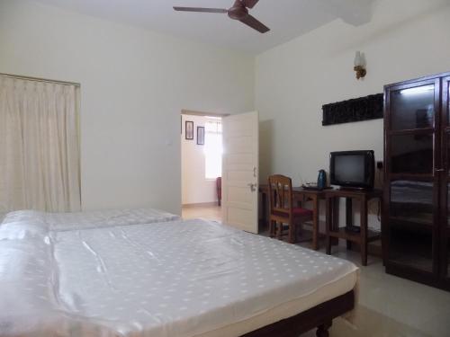 a bedroom with a bed and a desk and a tv at Safire Residency in Trivandrum