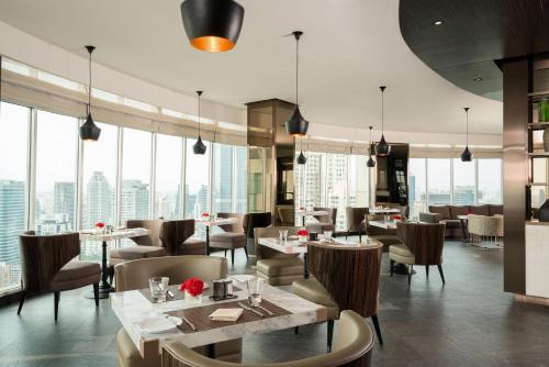 a restaurant with tables and chairs and large windows at JC Kevin Sathorn Bangkok Hotel in Bangkok