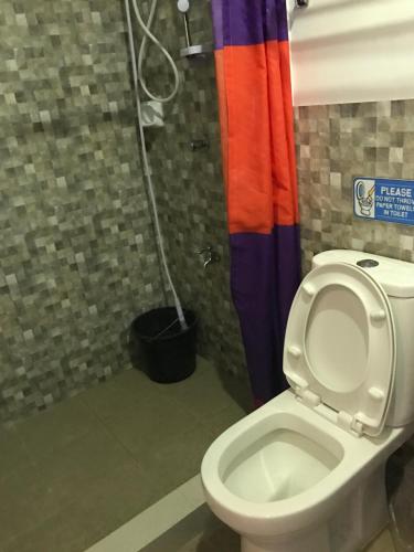 a bathroom with a toilet and a colorful shower curtain at Alzeah's Place Room for Rent in Tagaytay