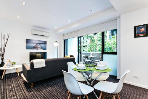 a living room with a couch and a table and chairs at Complete Host Halo Apartments in Melbourne