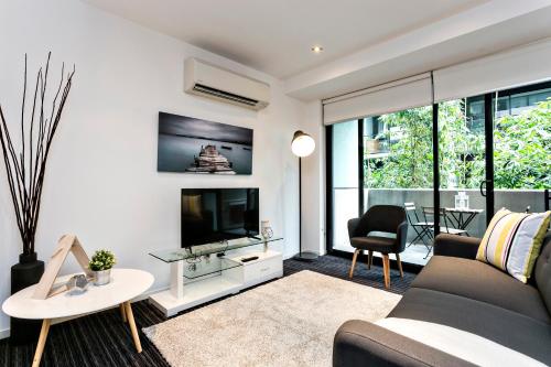 a living room with a couch and a tv at Complete Host Halo Apartments in Melbourne