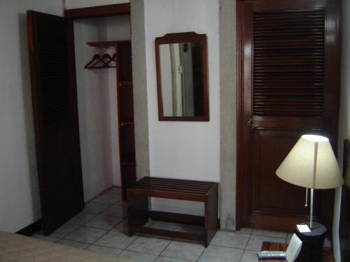 a room with a mirror and a lamp and a door at Dai Nonni Hotel in Guatemala