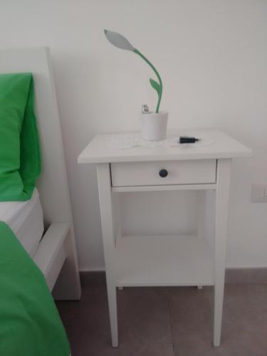 a white nightstand with a plant on it next to a bed at Casa Lucrino in Pozzuoli
