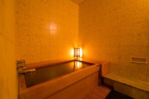 a bathtub in a bathroom with a light on the wall at Ibusuki Syusui-en in Ibusuki