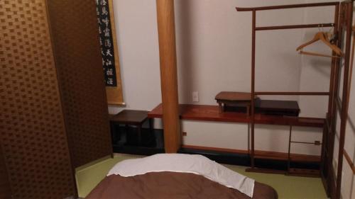 a room with a bed and a wooden shelf at Guest House Kuranomachi ゲストハウス蔵の街 in Tochigi