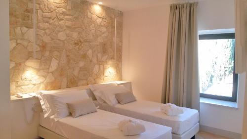 a hotel room with two beds and a stone wall at Giotto Country House & Spa in Assisi