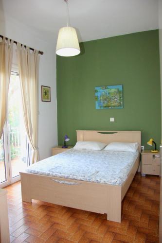 a bedroom with a bed and a green wall at Eleni Houses in Kómboi