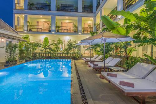 a hotel swimming pool with lounge chairs and an umbrella at Golden Citadel Hotel Siem Reap in Siem Reap