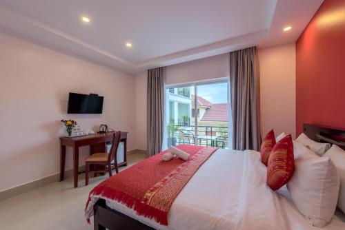um quarto com uma cama, uma secretária e uma janela em Golden Citadel Hotel Siem Reap em Siem Reap