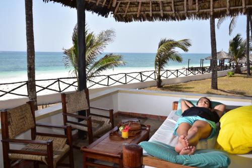 a woman laying on a bed in a room with the beach at Kilifi Bay Beach Resort in Kilifi