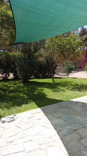 a patio with a green umbrella over a grass yard at La Contea in SantʼAnna Arresi