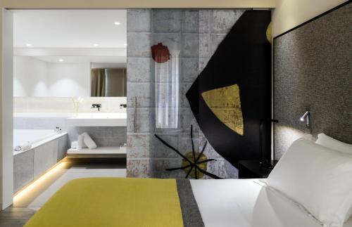 a bedroom with a bed and a bathroom with a tub at H10 Art Gallery 4* Sup in Barcelona