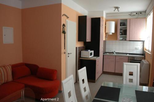 ein Wohnzimmer mit einem roten Sofa und einer Küche in der Unterkunft Monteur - Budget Apartments Freital in Freital