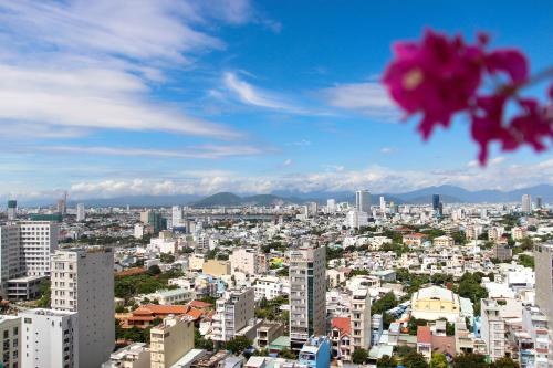 a city skyline with a pink flower in the foreground at Diamond Sea Hotel in Da Nang