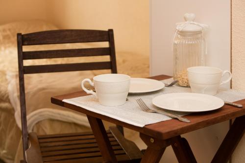 a wooden table with two cups and plates on it at Small Apartment in Sikupilli in Tallinn