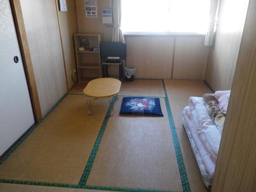 a small room with a bed and a book on the floor at Minshuku Iwakawa in Yakushima