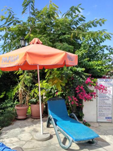 an orange umbrella and a blue chair under an umbrella at Kings Apartment with private Garden in Paphos City