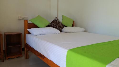 Schlafzimmer mit einem Bett mit weißer Bettwäsche und grünen Kissen in der Unterkunft Sigiri Lion Villa in Sigiriya